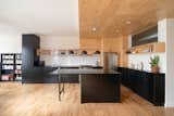 The kitchen countertops are black quartz, offering a strong visual contrast to the plywood. "Leïla and Xavier enjoy having friends over to sit at the kitchen island, which is the center of the space," says architect Catherine Milanese.