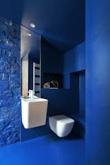 The white fixtures and fittings stand out against the bold blue bathroom walls.