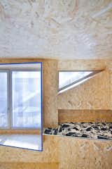 The triangular window above the kitchen lets natural light into the small space and creates a dynamic accent that breaks up the large OSB surface.