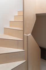 A roof window positioned above the double-height stair fills the space with natural light, which reflects off the light-colored birch plywood.