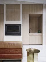 In the kitchen, oak joinery and a minimal fireplace sit within a neutral, low-cost pine plywood wall.
