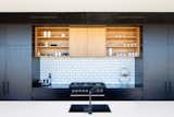 The handmade-look white brick tiles on the kitchen backsplash echo the brickwork used on the outdoor fireplace. They help to provide visual continuity from the exterior to the interior.