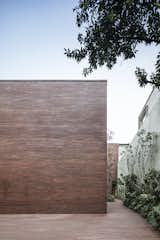 The slim profile of the red bricks used in the facade creates a textured surface across the monolithic form, while red and brown tones of each brick create an organic, varied pattern of color. 