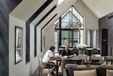 The deep-set dormer windows, which extend into the roof, have black interior surfaces, creating dramatic cut outs in the simple gabled form. The pendant above the kitchen counter is the Modo Chandelier by Roll &amp; Hill.