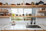 Extending the open shelves across the window in the kitchen maximized the area for storage, creating a visually appealing way to display the couple's collection of ceramic tableware. 