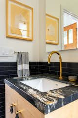 The dark tile used in the guest bathroom was chosen to both complement and create a quiet backdrop for the more expressive character of the marble. Elsewhere, light finishes help to reflect light around the space, making it feel brighter and more open.
