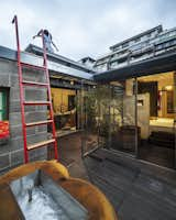 A red ladder, which echoes the vibrant color of the front door, leads to a simple rooftop deck.