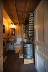 The bathroom features a freestanding tub made from an upcycled feeding trough from a farm, and a salvaged door. There is a composting toilet, and water comes from a 1000-liter rainwater tank located on the second floor.