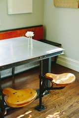 In the diner-style eating area, a custom aluminium table top is surrounded by salvaged-wood bench and vintage swivel seats.