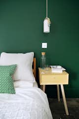 The primary bedroom is painted in Dulux Woodland Fern 1. The bedside lamp is a Carronade Nordic Spot Pendant by Le Klint. Eventually, the couple plan to add another floor and move the main bedroom upstairs.&nbsp;