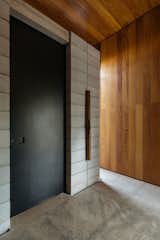 Industrial black metal doors—such as the entrance to the main suite—offset the internal timber cladding, reenforcing the contrast between the architecture and the interior.&nbsp;