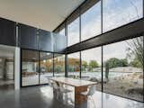 The bespoke dining table is crafted from a fallen silk oak found on the site. The large glazed doors open to the covered patio, extending the living space outside.