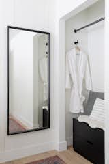 The guest bedrooms feature numerous amenities, including built-in closets. The clean lines of the black-framed mirror contrast with the more rustic shiplap walls.