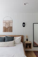 The two guest rooms feature queen beds, cozy textiles, and thoughtful conveniences for guests such as reading lamps and hanging hooks. "One way we married clean and rustic aesthetics was to install vertical shiplap behind the headboard in one of the rooms," says Tarah. "We chose boards in irregular sizes with a rough-hewn finish to add texture and dimension to the feature wall." 