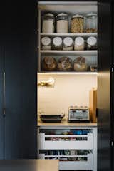 The pantry features black-stained timber doors that conceal appliances, keeping the kitchen surfaces clear.