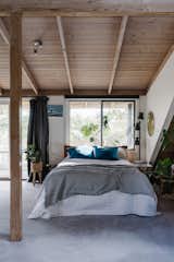 The master bedroom is located on the first floor and features a balcony overlooking a leafy canopy. The timber ceiling mirrors the one on the ground floor.