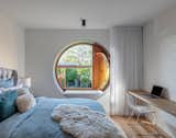 The principal bedroom in the Totoro House features a circular window that was inspired by the East Asian concept of shakkei. A small hatch allows fresh air to enter the interior, while a built-in cushion on the window frame acts as a small seat for the homeowners’ children.&nbsp;"The window allows the clients to be private, yet also connected to the rear courtyard," says architect Clinton Cole.