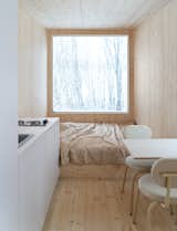 The Cabin is furnished with Delo Design’s TRU chairs in cream. The bed is nestled beneath a large window that frames the landscape, and a small kitchenette sits opposite the dining zone.