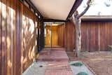 A brick walkway leads to the front door. A gridded skylight above the entrance fills the narrow space with light.  Photo 9 of 23 in A Glowing Midcentury by Jack Corey Asks $1.8 Million in Los Angeles