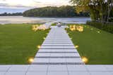 A perfectly manicured lawn is made even more alluring with the addition of a strikingly linear pathway that combines Techo-Bloc’s Blu Grande slab in Greyed Nickel with small pebbles. A paved fire pit area introduces an additional functionality to the pathway and creates an impressive spot to stop and admire the view. Discreet lighting makes sure the space can be appreciated at night as well as during the day.  Photo 13 of 15 in 10 Inspiring Landscaping and Outdoor Design Trends for 2022