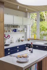 “I really wanted to recycle the original blue Boffi kitchen that came with the house to avoid unnecessary demolition and waste,” says architect Helena Rivera. “So, I designed the unit layout in a way that allowed all of those carcasses to be re-used, and intentionally ‘filled the gaps’ with three new joinery pieces—a larder, an island for our cookbooks, and a high-level appliance unit—that match the American walnut of the timber screen in the arrival hallway.”