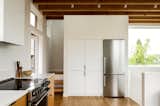 Kitchen, Engineered Quartz Counter, Refrigerator, Wood Cabinet, Medium Hardwood Floor, Cooktops, White Cabinet, and Ceiling Lighting Two Experimental Townhouses Clad in Cor-Ten Steel Add Density to a Seattle Neighborhood - Photo 5 of 19 - 