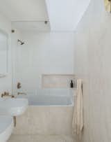 The main bathroom uses slabs of travertine contrasted against white subway tiles. “The master bathroom, which is cream and white with brass fixtures, is a favorite space,” says resident Fei Zhong. “We spent a lot of time scouting the right tiles and stone and decided on travertine. It creates a really peaceful space in a house with two small children.”