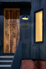 The texture of the reclaimed timber door contrasts with the industrial corrugated steel facade. “We rebuilt the exterior with dark grey corrugated steel and a tall front door to distinguish it a bit on the street from its neighbors,” says architect Aniket Shahane.