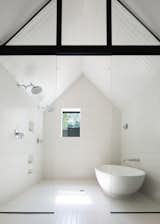 The master ensuite is nestled into the pitched roof form of the "inner house", a feature which is emphasized through the contrast of the white tiles and black structural elements.