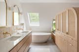 The former closet was transformed by opening up the wall to the bedroom and adding a skylight above the bathtub. The light timber joinery and bright white surfaces enhance the feeling of light.