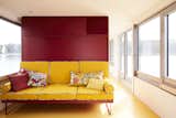 The sofa in the living room features bright yellow Kvadrat upholstery and patterned cushions made from textiles collected by Marianne. It is part of a unit that functions to divide the space, conceal the fold-away bed, and provide extra storage.