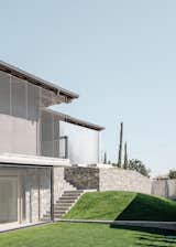 Italian design firm Archisbang transformed an unfinished family villa—acquired through a bankruptcy auction—into additional office space for a company called Chemsafe. The volume is wrapped in a metal mesh and the walls are clad in exposed wood fiber, concrete insulating panels, and galvanized metal sheets, creating a striking contrast between precise detailing and raw materiality.