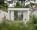 The roof of the garden house and the main extension are made of metal decking, which is left exposed inside. "Metal decking is almost never used for domestic projects, but it allowed us to create an articulated ceiling with linear ‘vaults’ or ‘waves’—instead of the boring, more traditional ‘cover it with gypsum boards’ approach," says architect Mariia Pashenko. "The waves of the decking create an architectural theme together with the waves of the metal facade panels and window curtains."