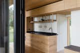 The kitchen features open upper cabinets crafted from timber leftover from Konga’s kitchen manufacturing, a zero-waste strategy implemented by Fredskild. The space includes a refrigerator, gas stove for cooking, sink, and ample storage. The push-to-open cabinets can also be used for long-term storage.