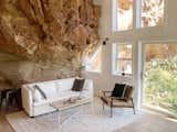 Inside, the home’s cliffside location becomes even more dramatic, with walls formed from the red rock itself. The rest of the interior and furnishings are kept purposefully minimalistic as a neutral backdrop to the natural beauty of the rock face. The shape of the rock has also been used to define the interior architecture—take, for example, the book nook hidden in a natural alcove.