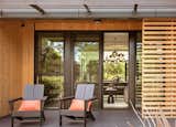 The covered porch is furnished with comfortable seats that allow the residents to engage with neighbors, while the timber screen helps maintain privacy for the interior.