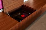 The LP turntable is concealed under a walnut bench, which allows the family to use the space for multiple purposes. When they want to enjoy their extensive record collection, they can simply open up the bench to reveal the record player.