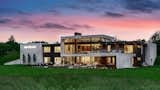 From the rear, the home dramatically reveals its true scale. Two levels are set into the hillside site, and the rear facade is almost entirely glass divided by an undulating band of white stucco.