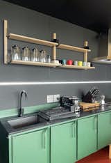The green kitchen cabinetry provides a bold accent of color that complements the bright orange rubber flooring. The bespoke kitchenette was a collaboration with South African design studio Dokter and Misses.  Photo 13 of 16 in Budget Breakdown: This Remote Prefab Hideaway Built From Shipping Containers Cost $300K