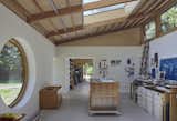 The studio comprises two equally sized spaces—one for Miriam and one for Simon—connected by double doors. The in-between space acts as storage, a small kitchenette, and Miriam’s dark room. Each studio space has been designed to meet the specific needs of the artist. Miriam’s space, for example, is punctuated by an enormous round window that allows her to draw inspiration from the surrounding landscape, while the walls in Simon’s space are dedicated to timber and tool storage.