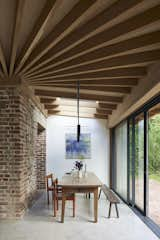 The extension wraps around the brick walls of the original home. It features large glazed doors that slide open to the verandah for seamless indoor-outdoor living when the weather allows. The dining table has been in Miriam's family for several generations, and is paired with some “very battered” midcentury Magistretti chairs.