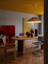 This apartment in Sydney by Studio Prineas features a moody palette of yellows, oranges, and reds. The dining area is furnished with an August Table by Australian design brand Jardan, a Cab Chair by Cassina, and blue Thonet Gmbh S 43 chairs. The yellow and red artworks are from Gemma Smith’s 2023 Plural series.