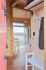 The bright red front door opens to a small entry hall with storage and seating. This leads directly to the open-plan living, dining, and kitchen space. The furniture throughout is primarily from affordable Australian retailer Early Settler.
