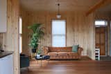 The light timber wall lining and large vertical windows make the compact living room feel spacious. Lev kept lighting consistent throughout, using “schoolhouse” pendant fittings to unify the interior and keep costs down.