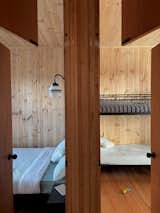 The floorplan prioritises simplicity, with the bedrooms located next to each other, each occupying a corner of the modest house. The wall-mounted lighting in the bedrooms and bathrooms echoes the pendant lighting used in the living areas, creating a sense of consistency.