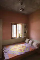 The bedroom on the ground floor features in-built shelving and a bed frame built using scrap timber.
