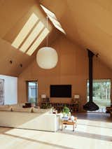 The living space is inspired by traditional barn interiors with soaring ceilings. The interior is clad almost entirely in white oak, including the floors, ceiling panels, and the trim around the windows and doors. "I consulted a German friend of mine and said, ‘I'm thinking of Baltic, birch, and oak,’" says homeowner and designer Michael Halpern. "And he said, ‘Oh, the German expression is ‘aus einem Guss.’ Or ‘in one pour.’ And I thought that sounds right. So it became all oak."