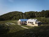 Two barn structures sit perpendicular to one another with a glass entry foyer connecting them.