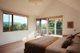 The view from the primary suite offers a distinctly different perspective over the treetops compared to the ground floor spaces. The lower ceilings in the more private wing of the home are another contrast with the grand scale of the living areas, creating a cozier, more secluded feeling.