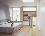 A short flight of stairs connects the study and the primary bedroom suite, with a palette of natural oak and white walls visually connecting the two spaces.
